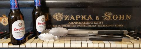 Bier und Fleischzange auf Klaviertastatur