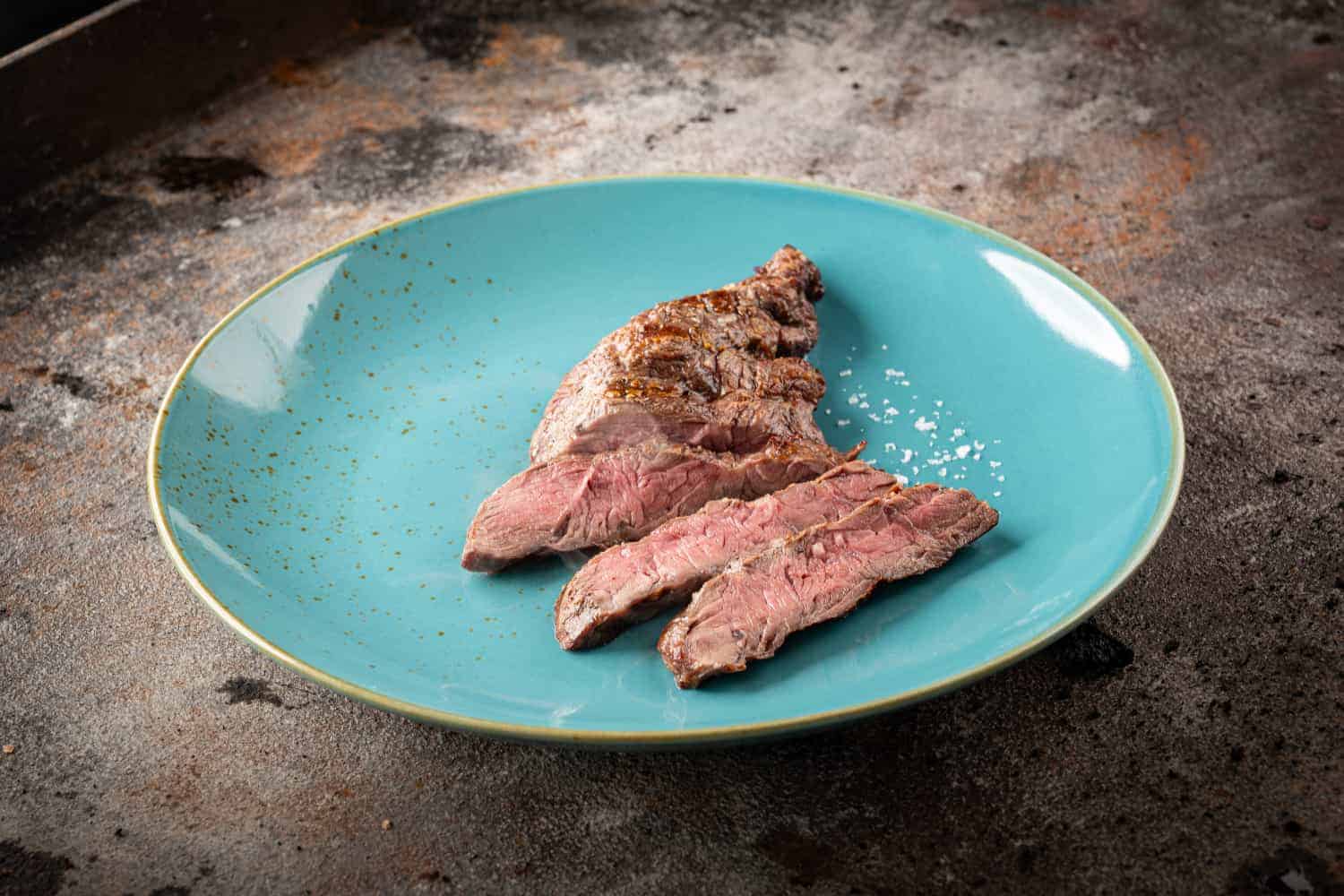 Tranchiertes gegrilltes Spider Steak auf einem blauen Teller.