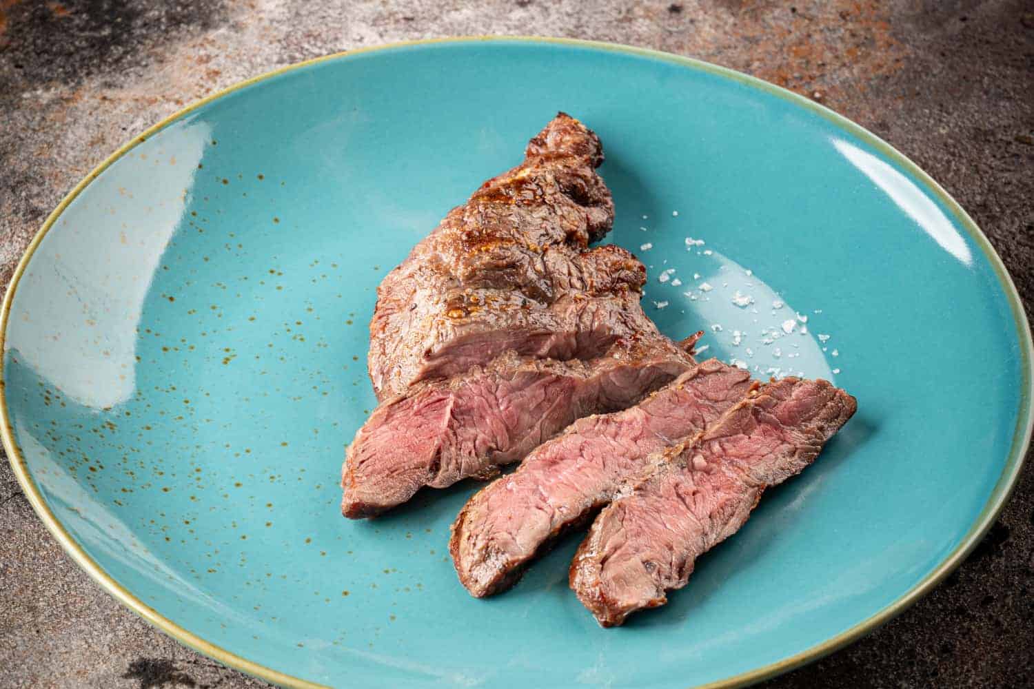 Tranchiertes gegrilltes Spider Steak auf einem blauen Teller.