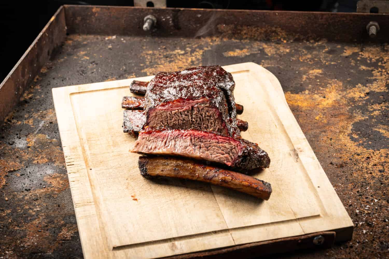 Saftige Short Ribs aus dem Smoker, aufgeschnitten auf einem Holzbrett